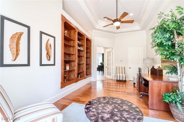 office with ceiling fan, a raised ceiling, light wood-style floors, and ornamental molding