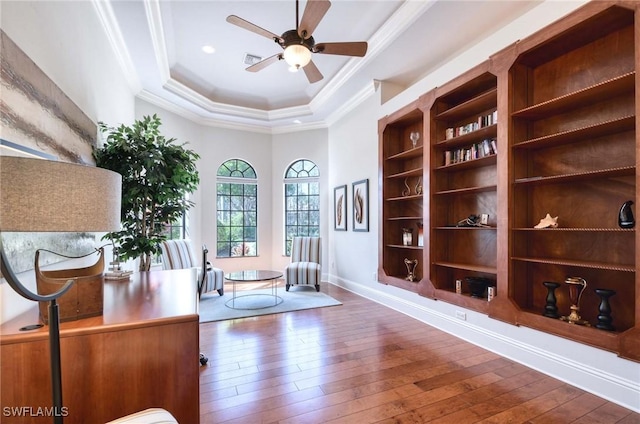 home office featuring a tray ceiling, wood-type flooring, ceiling fan, and crown molding