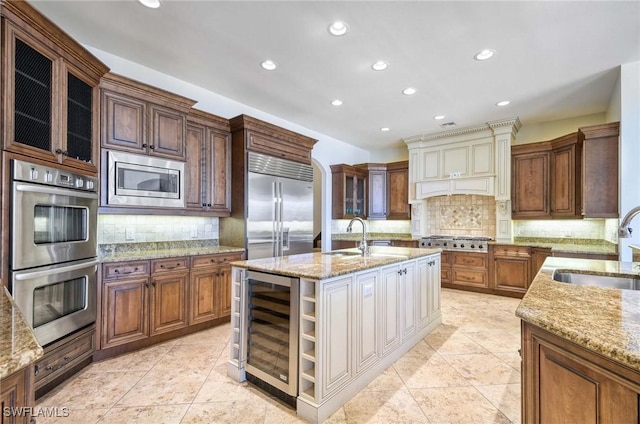 kitchen featuring custom exhaust hood, beverage cooler, built in appliances, and a sink