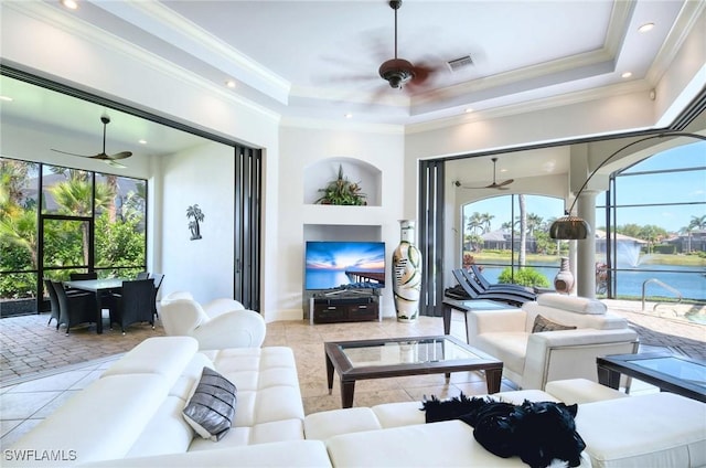 living area with visible vents, crown molding, ceiling fan, tile patterned floors, and a raised ceiling