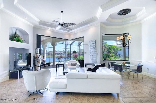 living area with a wealth of natural light, a tray ceiling, and ceiling fan with notable chandelier