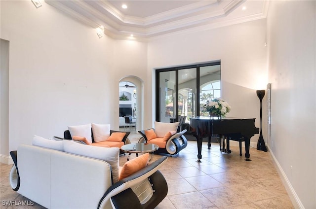 living area with baseboards, ornamental molding, light tile patterned floors, a high ceiling, and arched walkways