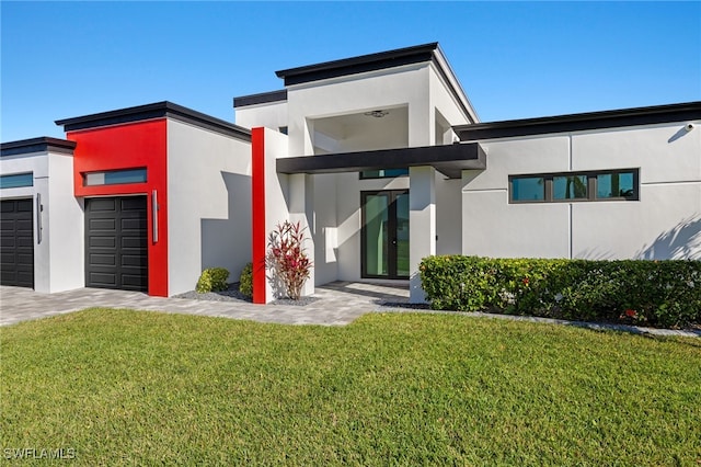 view of front facade with stucco siding, an attached garage, and a front yard