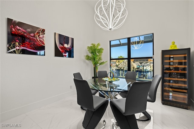 dining room featuring wine cooler, a notable chandelier, baseboards, and marble finish floor