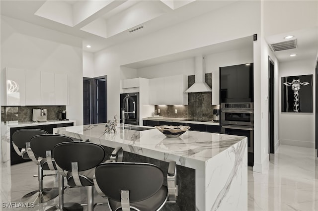 kitchen with visible vents, black appliances, marble finish floor, modern cabinets, and wall chimney exhaust hood