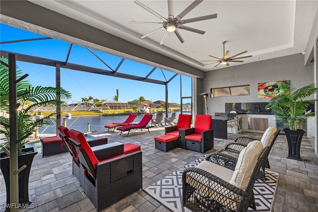 view of patio with a water view, ceiling fan, exterior kitchen, an outdoor hangout area, and a lanai