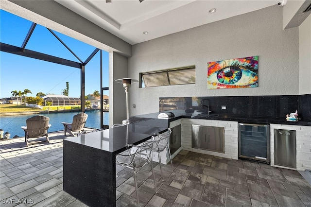 kitchen with beverage cooler, recessed lighting, a sunroom, a sink, and dark countertops