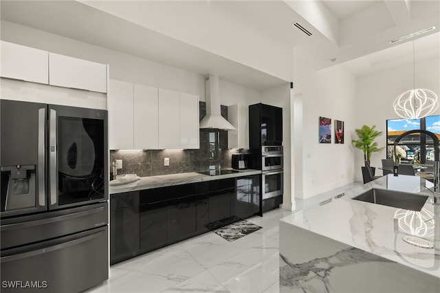 kitchen with marble finish floor, white cabinetry, stainless steel appliances, and wall chimney range hood