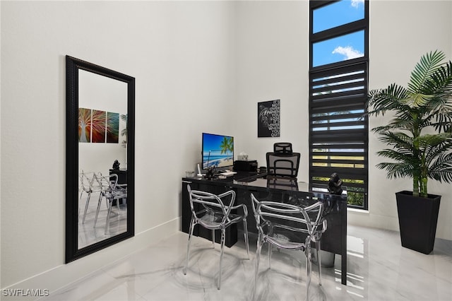 office with marble finish floor, baseboards, and a towering ceiling