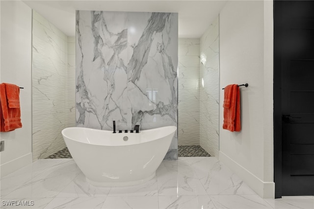 bathroom with stone wall, a soaking tub, marble finish floor, and a walk in shower