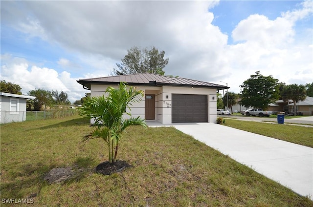 view of front of home with a front lawn, a standing seam roof, concrete driveway, an attached garage, and metal roof