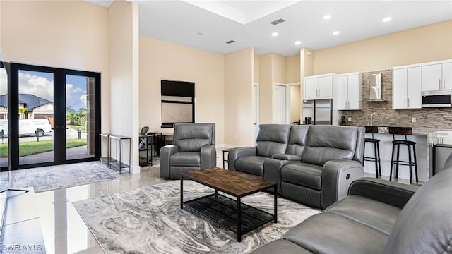 living area with a high ceiling, recessed lighting, and visible vents