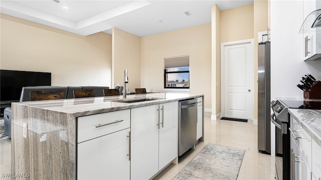 kitchen with white cabinets, light stone countertops, appliances with stainless steel finishes, and a sink