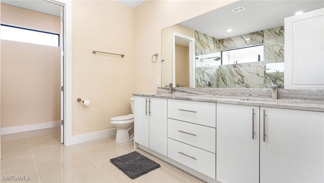 bathroom featuring a marble finish shower, baseboards, toilet, double vanity, and a sink