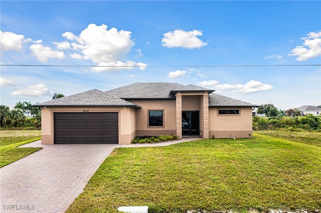 prairie-style home with a garage, stucco siding, decorative driveway, and a front lawn