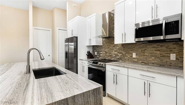 kitchen with a sink, tasteful backsplash, stainless steel appliances, wall chimney exhaust hood, and white cabinets