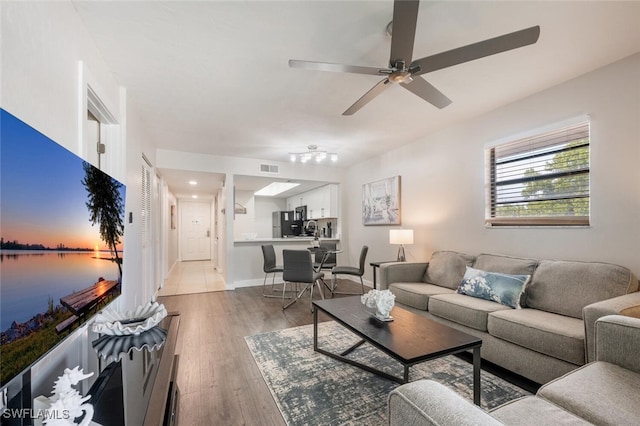 living area featuring ceiling fan, baseboards, and wood finished floors