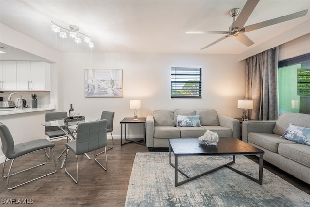 living area with dark wood-style floors, baseboards, and ceiling fan