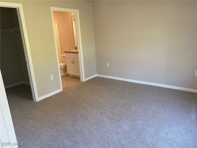 unfurnished bedroom featuring baseboards, light carpet, a closet, and a spacious closet