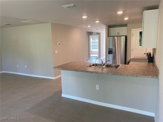 kitchen with visible vents, baseboards, a peninsula, stainless steel refrigerator with ice dispenser, and a sink