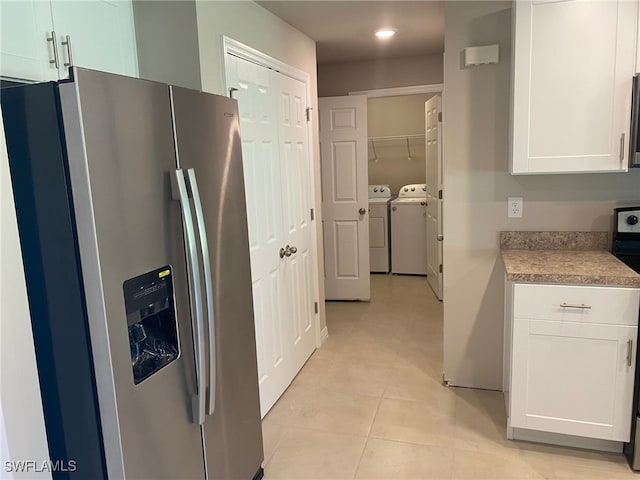 kitchen featuring light tile patterned floors, stainless steel appliances, light countertops, white cabinets, and washer and dryer