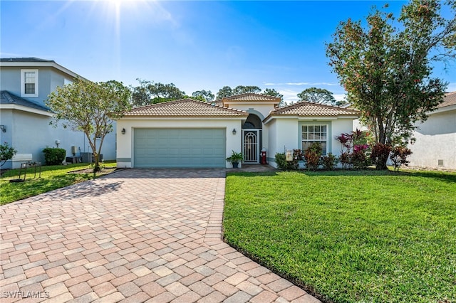 mediterranean / spanish home with a front yard, stucco siding, a garage, a tiled roof, and decorative driveway