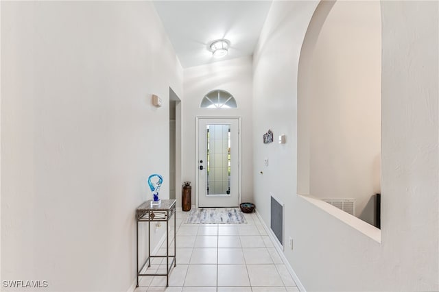 foyer with light tile patterned floors, visible vents, arched walkways, and baseboards