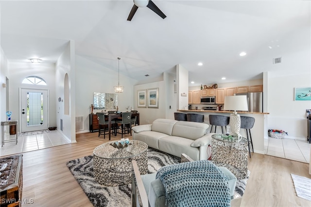 living room featuring visible vents, arched walkways, ceiling fan, vaulted ceiling, and light wood-type flooring