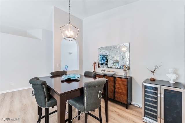 dining area with an inviting chandelier, beverage cooler, baseboards, and light wood finished floors