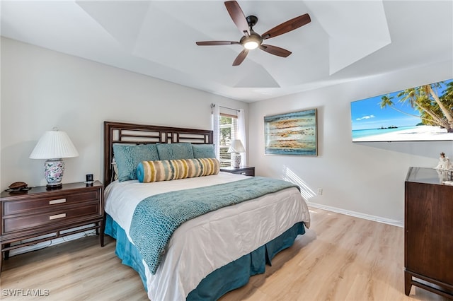 bedroom featuring a tray ceiling, baseboards, and wood finished floors