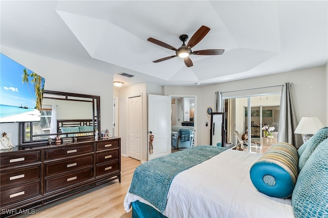 bedroom featuring visible vents, light wood-style flooring, ceiling fan, a raised ceiling, and access to outside