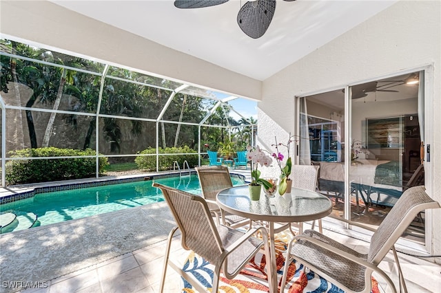 outdoor pool with a patio area, glass enclosure, and ceiling fan