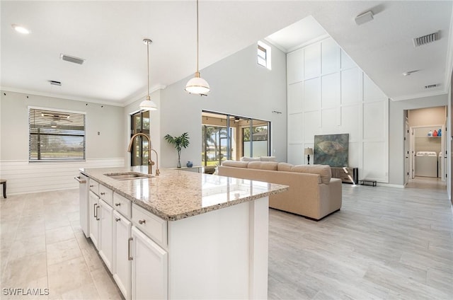 kitchen featuring a sink, visible vents, washer / clothes dryer, and a healthy amount of sunlight