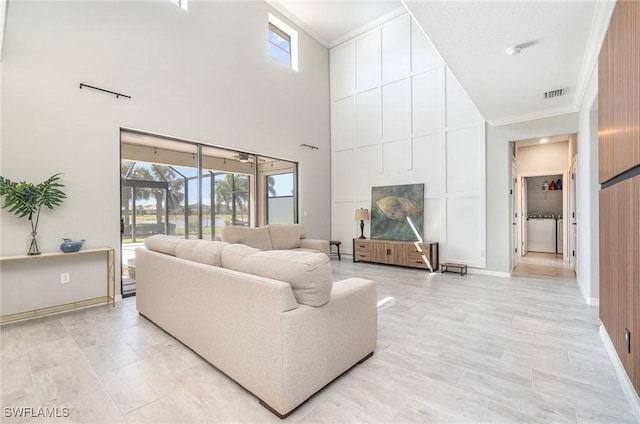 living room with crown molding, a high ceiling, baseboards, and visible vents