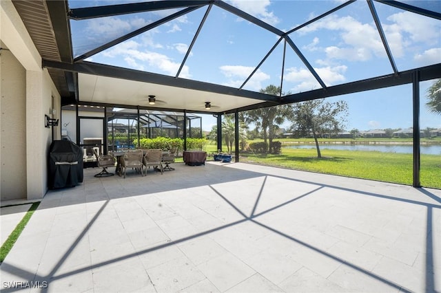 view of patio / terrace featuring area for grilling, glass enclosure, and a water view