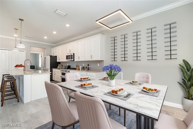 kitchen with an island with sink, decorative backsplash, white cabinets, appliances with stainless steel finishes, and a kitchen bar