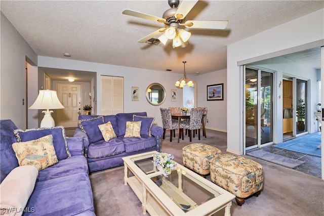 carpeted living area featuring baseboards, a textured ceiling, and ceiling fan with notable chandelier