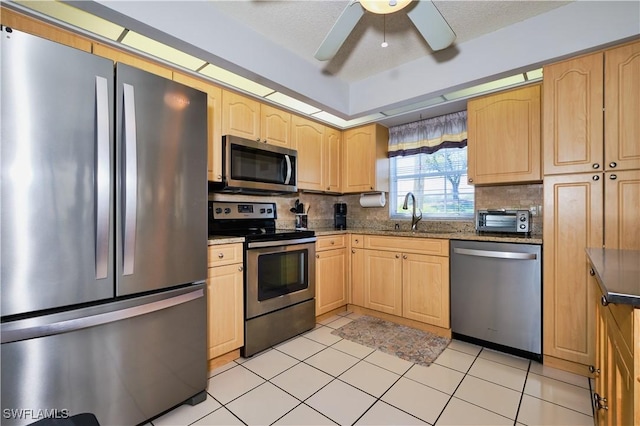 kitchen with tasteful backsplash, ceiling fan, light brown cabinetry, stainless steel appliances, and a sink