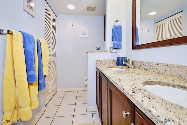 bathroom featuring tile patterned flooring, visible vents, toilet, double vanity, and a sink