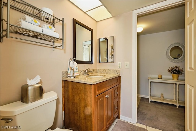 bathroom with baseboards, toilet, and vanity