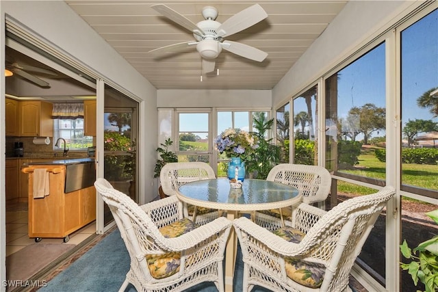 sunroom featuring a ceiling fan and a sink