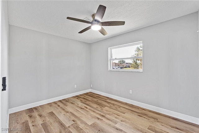 empty room with ceiling fan, baseboards, a textured ceiling, and wood finished floors