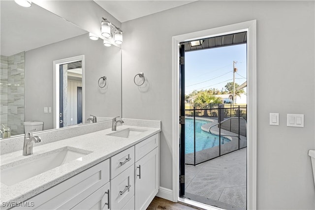 full bathroom with a sink, baseboards, toilet, and double vanity