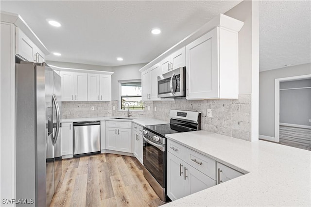 kitchen featuring a sink, appliances with stainless steel finishes, white cabinets, and light countertops