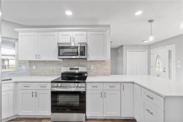 kitchen featuring white cabinetry, appliances with stainless steel finishes, a peninsula, and light countertops