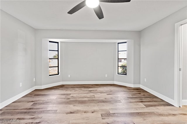 spare room featuring baseboards, wood finished floors, and a ceiling fan