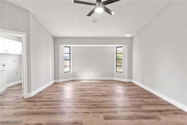 unfurnished room with light wood finished floors, visible vents, baseboards, a textured ceiling, and a ceiling fan