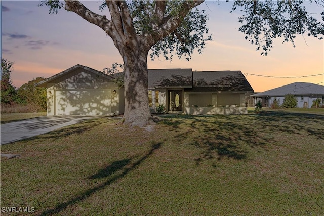 view of front of home featuring concrete driveway, a yard, and an attached garage