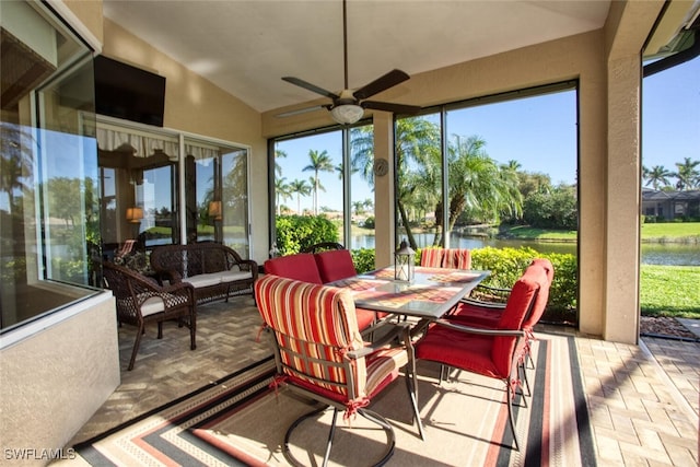 sunroom featuring vaulted ceiling, a ceiling fan, and a water view