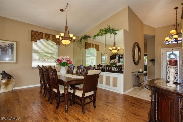 dining space featuring wood finished floors, a wealth of natural light, lofted ceiling, and a chandelier